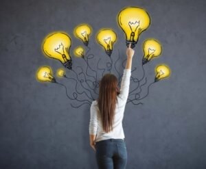 mulheer jovem diante de um quadro com várias lampadas acesas representando ideias