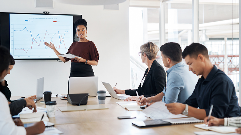 Executiva apresenta os dados projetados em uma tela para equipe